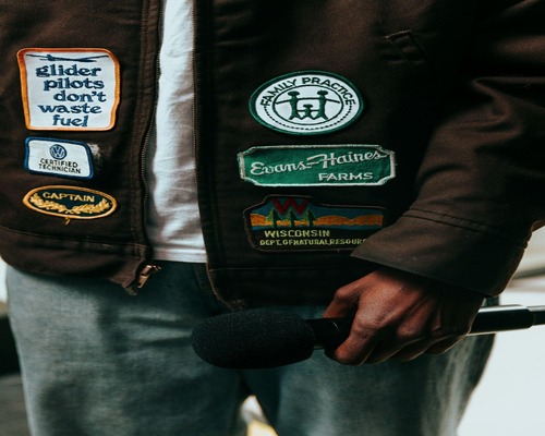 Brown jacket with patches, including mountains and number 73, showcasing creative patch placement ideas.