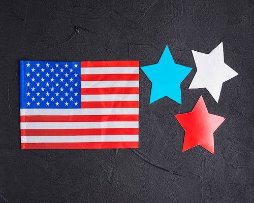 Alt text: U.S. flag with red, white, and blue star cutouts on black textured background.









