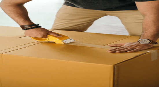 Person sealing a large cardboard box with packing tape for shipping.