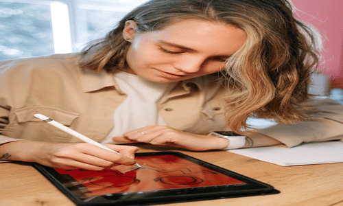 Person using a digital tablet and stylus to create a personalized Halloween patch design.