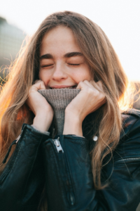 Woman in jacket and sweater covering face, showing warmth and layering in cold weather