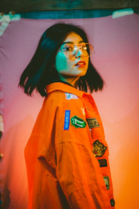Portrait of a person in an orange jacket with various colorful patches on the sleeve.