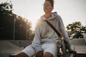 Skater in a grey hoodie sitting at a park, showing style variations for hoodie materials.