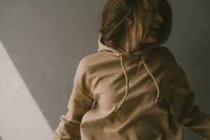 Laughing woman in a tan hoodie, illustrating why hoodie material quality matters