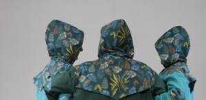 Three people facing away, wearing hooded jackets with matching leafy, tropical patterns.